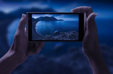 Kız geceleri deniz koyunun fotoğrafını çekiyor.