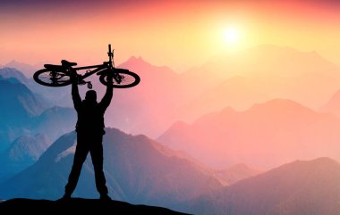 Bisikletçi, dağ vadisinde güneşin görkemli doğuşuna karşı bisikletiyle önündeydi. Aşırı spor ve bisiklet konsepti.