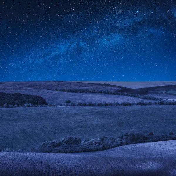 Colorful rolling spring fields in a moonlight at night. Majestic Ukrainian nature.