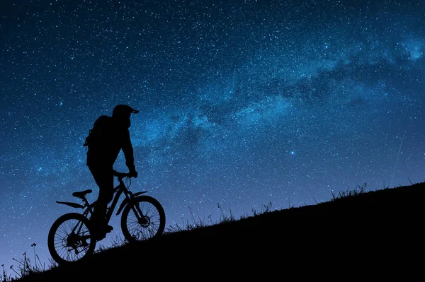 夜空の明るい天の川に対する自転車のサイクリストのシルエット — ストック写真