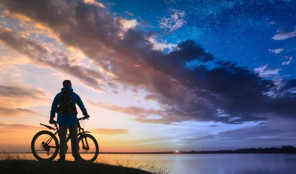 昼と夜の間の自転車とサイクリストのシルエット おとぎ話のような風景 — ストック写真