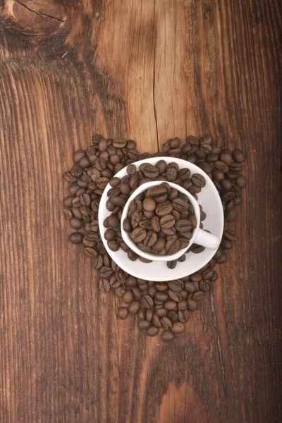 Graines de café brunes rôties & tasse sur table en bois — Photo