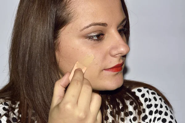 Mujer aplicando la fundación en la cara con esponja — Foto de Stock