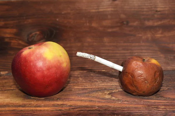 Zwei Äpfel und eine Zigarette im Holzhintergrund. Rauch tötet — Stockfoto