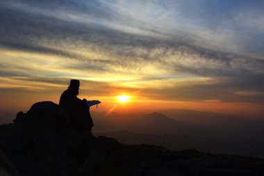 gün batımı ışığında, Romanya okuma rahip silüeti