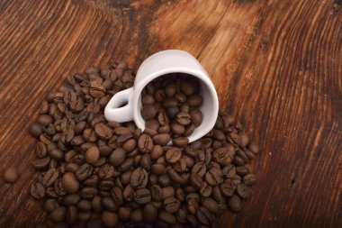 Kavrulmuş kahverengi kahve çekirdekleri ve kupa ahşap tablo