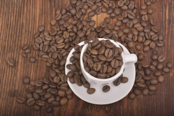 Café tostado frijoles y taza en mesa de madera —  Fotos de Stock