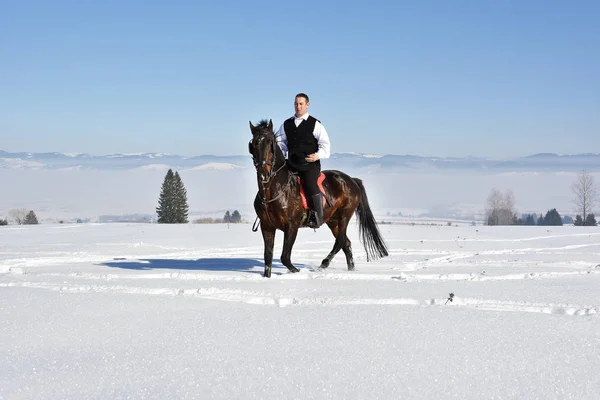 若い男が馬を冬に屋外に乗って — ストック写真