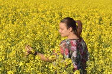 İlkbaharda çiçek açan kolza tohumu sahada genç mutlu kadın