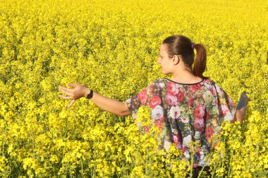 İlkbaharda çiçek açan kolza tohumu sahada genç mutlu kadın