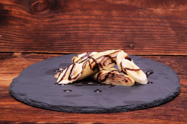 Crepe con plátano y chocolate en soporte redondo de pizarra — Foto de Stock