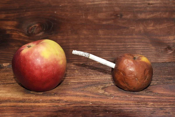 Zwei Äpfel und eine Zigarette im Holzhintergrund. Rauch tötet — Stockfoto