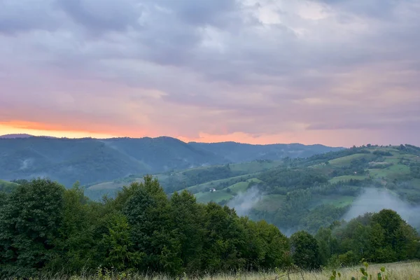 Noite e pôr do sol em colinas de montanha de uma aldeia romena — Fotografia de Stock