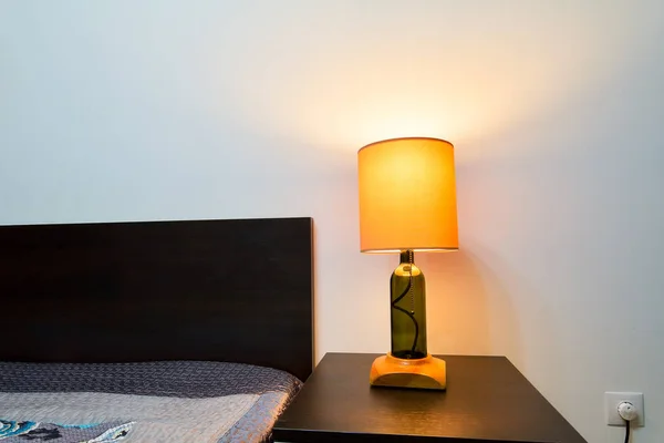 Lamp on a night table next to a bed