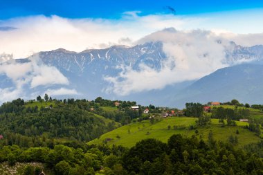 Güneşin doğuşunda yeşil tarlaları olan, bulutlu, güzel renklerde bulutlu bir gökyüzü olan kırsal bölge.