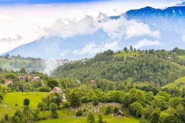 Güneşin doğuşunda yeşil tarlaları olan, bulutlu, güzel renklerde bulutlu bir gökyüzü olan kırsal bölge.