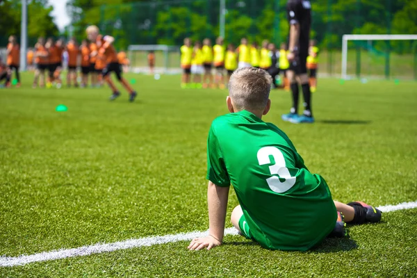 Jovem jogador de futebol caucasiano sentado na grama. Juventude futebol fundo — Fotografia de Stock