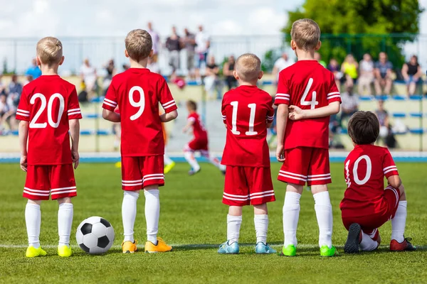孩子们的足球足球比赛。年轻的男孩的足球足球队看青年足球赛在运动场上。孩子们玩暑期学校足球锦标赛 — 图库照片