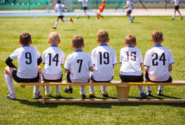 Genç futbolcular. Tahta bankta oturan genç futbol takımı. Çocuklar için futbol maçı. Turnuva futbol maçı oynayan genç erkek. Gençlik futbol kulübü futbol takımı oyuncuları