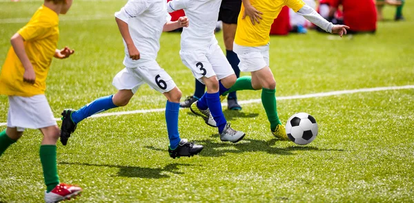 Crianças jogam futebol Match. Jovens rapazes chutando bola de futebol o — Fotografia de Stock