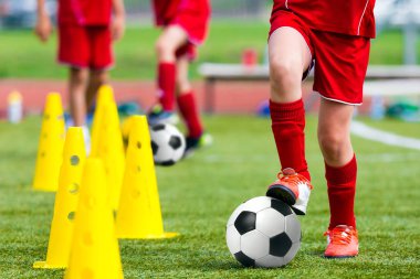Futbol futbol Training.Young atlet futbol topu ile sahada çocuklar. Kırmızı futbol topu Tekdüzen tekme çocuk. Çocuk pratik matkaplar spor çim sahada top sürme