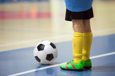 Futbol futsal eğitim çocuklar için. Kapalı futbol bir spor salonunda bir futbol topu ile genç oyuncu. Mavi ve sarı Tekdüzen oyuncunun. Spor arka plan.