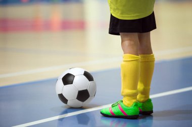 Futbol futsal eğitim çocuklar için. Kapalı futbol bir spor salonunda bir futbol topu ile genç oyuncu. Oyuncu sarı üniformalı. Spor arka plan.