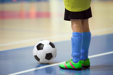 Futbol futsal eğitim çocuklar için. Kapalı futbol bir spor salonunda bir futbol topu ile genç oyuncu. Sarı ve mavi üniforma oyuncu. Spor arka plan.