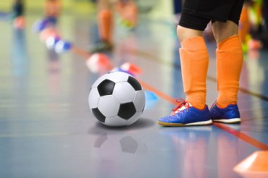 Futbol futsal kapalı spor salonu eğitim çocuk. Futbol topu eğitim kapalı futbol genç çocuk. Küçük oyuncu ışık turuncu spor çoraplar