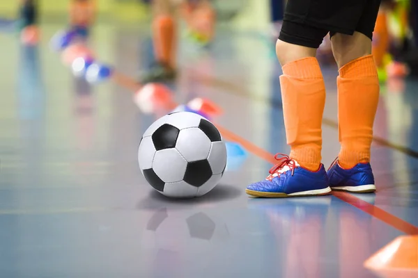 Niños entrenando fútbol futsal gimnasio interior. Niño con entrenamiento de pelota de fútbol fútbol interior. Pequeño jugador en calcetines deportivos naranja claro — Foto de Stock