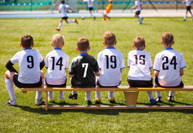 Futbol oyuncuları maç oyun. Tahta bankta oturan genç futbol takımı. Çocuklar için futbol maçı. Turnuva futbol maçı oynarken küçük çocuklar. Gençlik futbol kulübü futbol takımı oyuncuları