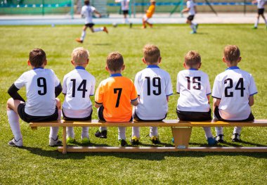 Genç futbolcular. Tahta bankta oturan genç futbol takımı. Çocuklar için futbol maçı. Turnuva futbol maçı oynayan genç erkek. Gençlik futbol kulübü futbol takımı oyuncuları
