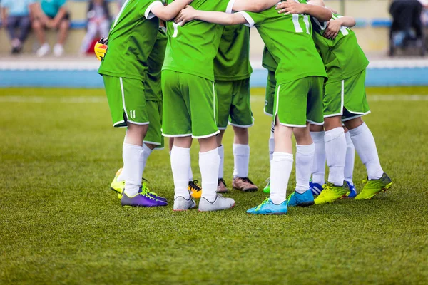 Jóvenes futbolistas en ropa deportiva verde. Equipo deportivo joven en lanzamiento. Charla de despedida antes del partido final. Torneo escolar de fútbol. Niños en el campo de deportes . — Foto de Stock