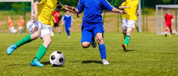 Fotbollspelarna kör och sparka boll på idrottsplats. Unga pojkar spelar fotboll på planen. Fotbolls turneringen ungdomstävling — Stockfoto