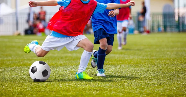 Genç erkek futbol topu tekmeleme yeşil Saha çimen. Futbol Okulu turnuva çocuklar için. Kırmızı ve mavi forma gömlek top için mücadele oyuncular