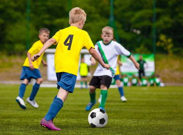 मुले सॉकर बॉल किकिंग. मुले फुटबॉल संघ. लहान मुले फुटबॉल खेळपट्टीवर बॉल घेऊन धावतात. क्रिया मध्ये युवा फुटबॉल खेळाडू — स्टॉक फोटो, इमेज