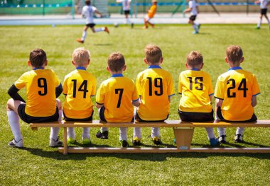 Genç futbolcular. Tahta bankta oturan genç futbol takımı. Çocuklar için futbol maçı. Turnuva futbol maçı oynayan genç erkek. Gençlik futbol kulübü futbol takımı oyuncuları