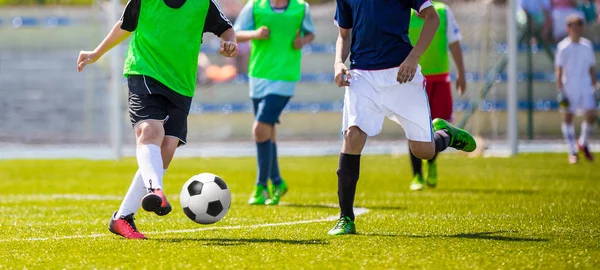 Jovens jogadores de futebol correndo após a bola no campo. Jogo de futebol entre duas equipes de jovens. Competição de esportes ao ar livre. Estádio de futebol no fundo — Fotografia de Stock