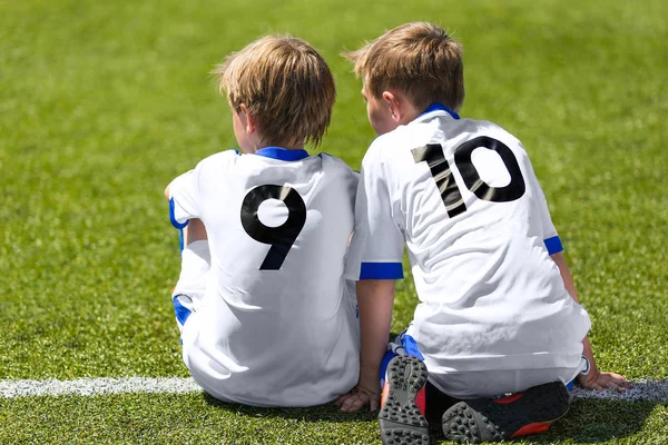 Jóvenes jugadores de fútbol. Niños sentados en el campo de fútbol. Jugadores de fútbol juvenil en camiseta de fútbol blanco — Foto de Stock