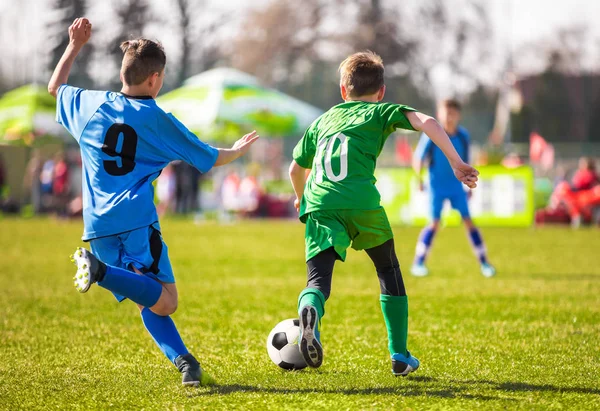 Los niños pateando pelota de fútbol en el campo de hierba verde vivo. Campo de fútbol en el fondo. Fondo futbolístico. Liga de fútbol juego —  Fotos de Stock