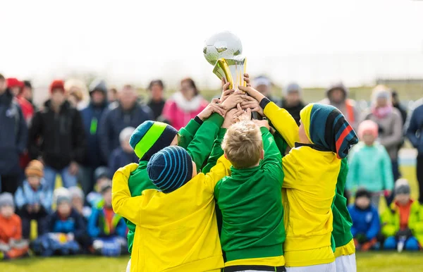 Nuoret jalkapalloilijat pitävät pokaalia. Pojat juhlivat jalkapallon mestaruutta. Winning Youth Team of Sport Turnaus lapsille lapsille. Lapset urheilun mestareina — kuvapankkivalokuva