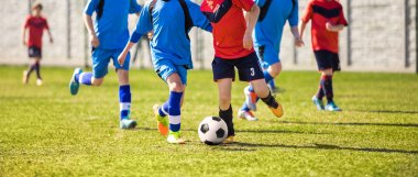 Genç erkek futbol oyuncuları Futbol Spor sahada tekme. Mavi ve kırmızı forma gömlek çalışan futbolcular. Gençlik futbol yatay arka plan