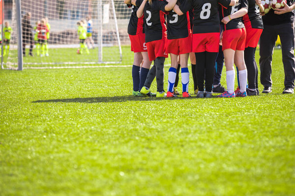Children's Football Team on the Pitch. Girls in Black and Red Soccer Kits Standing Together on the Football Field. Motivated Young Soccer Players with Coach Talking Before the Final Game of School Tournament