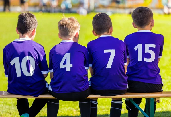 Equipa Desportiva Infantil. Young Boys Sitting on Soccer Bench and Watching Football Match (em inglês). Torneio de futebol para crianças. Educação Esportiva para Crianças — Fotografia de Stock