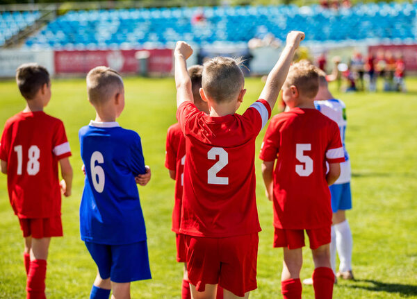 Happy Boys Winning Soccer Match. Young Successful Soccer Football Players on the Pitch. Winner Child Holding Hands Up