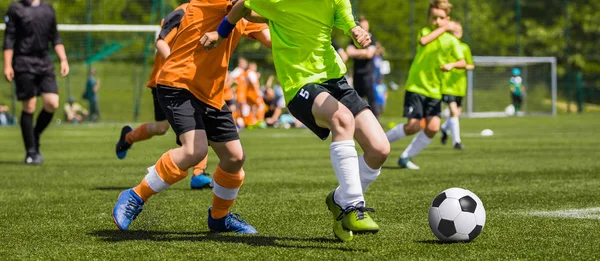 Молодые парни играют в футбол на поле. Дети бегают и пинают футбольный мяч на зеленой траве. Детская футбольная игра — стоковое фото