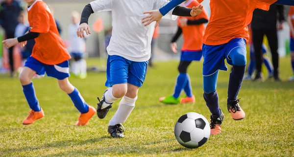 Dois Jogadores De Futebol Chutando Bola De Futebol Em Um Jogo. Meninos Da  Escola Jogam Competição Esportiva. Duas Crianças Multirraciais Jogando  Partida De Futebol. Crianças Em Uniformes De Futebol Verde E Azul