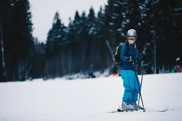 山の斜面の女性スキーヤー。バック グラウンドで暗い森を凍結します。ダウンヒル スキー冬森の山の中でスキーヤー — ストック写真