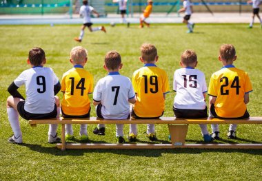 Genç futbolcular. Tahta bankta oturan genç futbol takımı. Çocuklar için futbol maçı. Turnuva futbol maçı oynayan genç erkek. Gençlik futbol kulübü futbol takımı oyuncuları