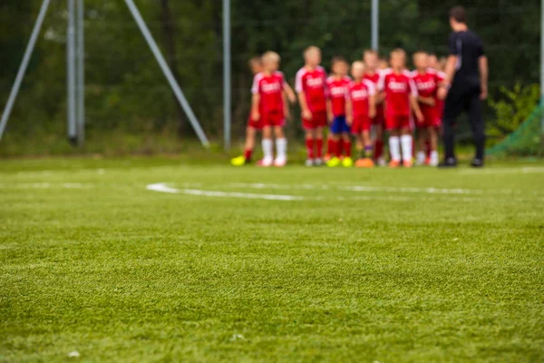 Youth Football Team with Coach on Pitch; Blurred Soccer Background (em inglês). Sessão de Treinamento de Futebol para Crianças — Fotografia de Stock